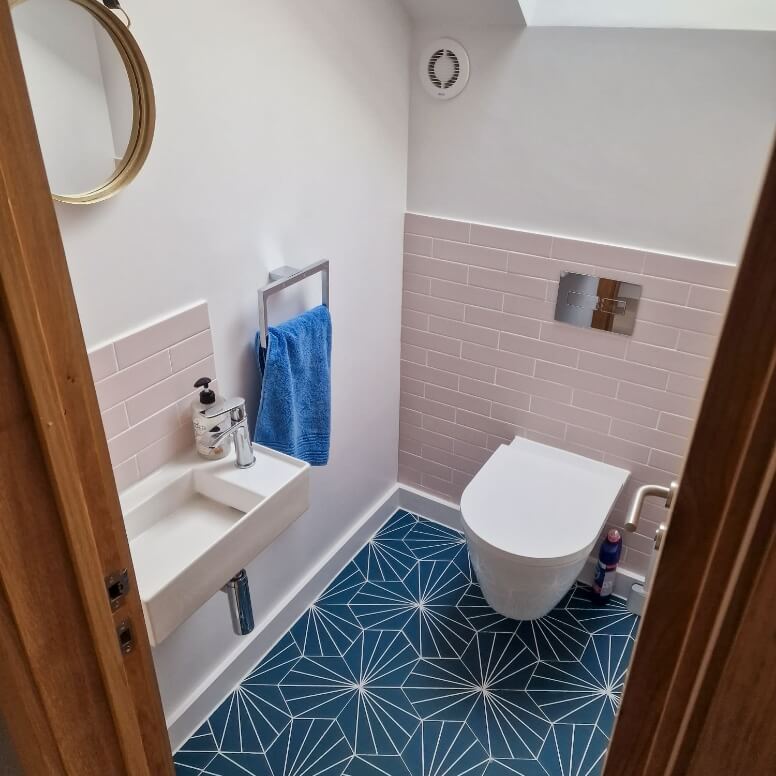 WC with white toilet and sink, pink tiles and blue patterned floor